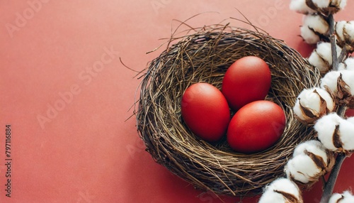 pastel red easter eggs in bird s nest on pastel red background with cotton branches top view easter composition with copy space in flat lay minimalist style happy easter concept for design photo