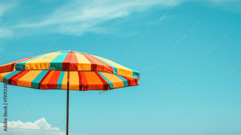colorful striped beach umbrella under clear blue sky for summer vacation theme, with copy space for text