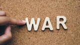 war wood word on compressed or corkboard with human s finger at r letter