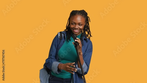 Portrait of african american motivational speaker talking in microphone, addressing audience, isolated over studio background. Expressive lecturer using mic, inspiring motivation, camera A