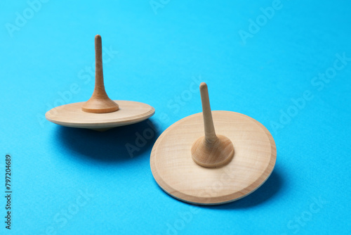 Two wooden spinning tops on light blue background