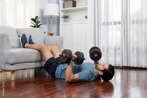Athletic body and active sporty man using furniture for effective targeting muscle gain with weight lifting dumbbell exercise at gaiety home as concept of healthy fit body home workout lifestyle.
