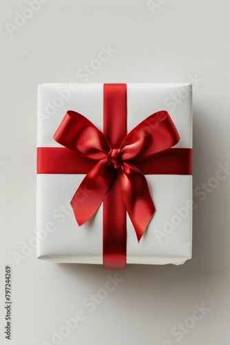 A red ribbon adorns the white present against a white backdrop. © tonstock