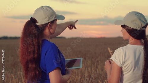 Women farmers working in wheat field, working in team of business women. Two farmers sign contract in wheat field using tablet. Working in team of business partners. Agricultura, Modern technologies