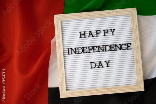 HAPPY INDEPENDENCE DAY text frame on United Arab Emirates waving flag made from silk material. Commemoration Day Muslim Public holiday celebration background. The National Flag of UAE. Patriotism