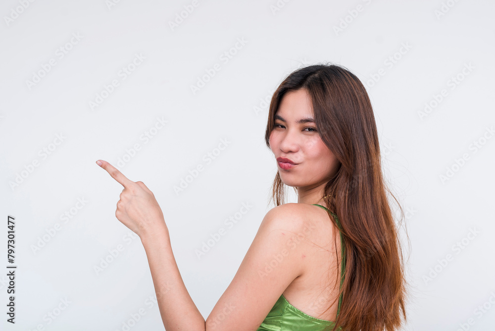 Charming woman in green silk dress pointing and puckering lips, isolated on white Charming woman in green silk dress pointing and puckering lips, isolated on white