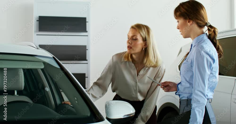 A stylish woman chooses a car at a car dealership. The manager talks to the client showing the cars A stylish woman chooses a car at a car dealership. The manager talks to the client showing the cars
