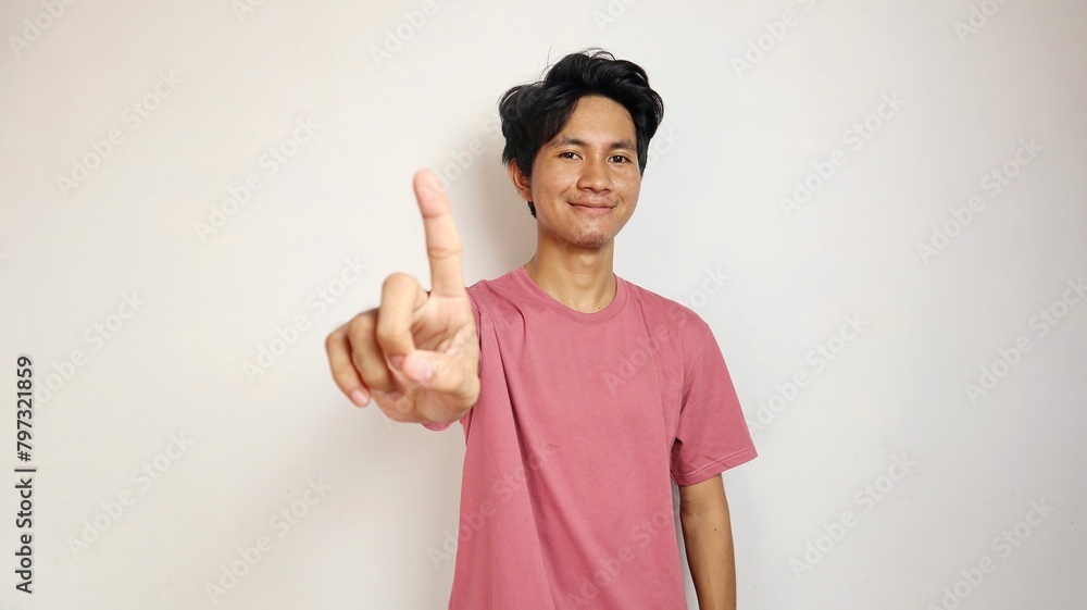 smiling young asian man posing showing the number 1 with his finger on an isolated white background smiling young asian man posing showing the number 1 with his finger on an isolated white background