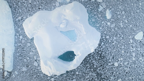 Close-up iceberg. Aerial zoom drone flight. Antarctica landscape. Top down overview of ice mountain. Pieces of frozen ice in polar ocean water. Antarctic continent. Zooming out.