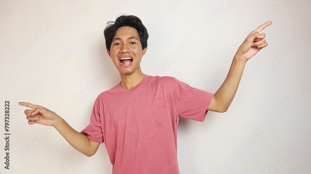 Excited young handsome Asian man happy, cheerful and enthusiastic posing pointing to the left and right side with an isolated white background Excited young handsome Asian man happy, cheerful and enthusiastic posing pointing to the left and right side with an isolated white background