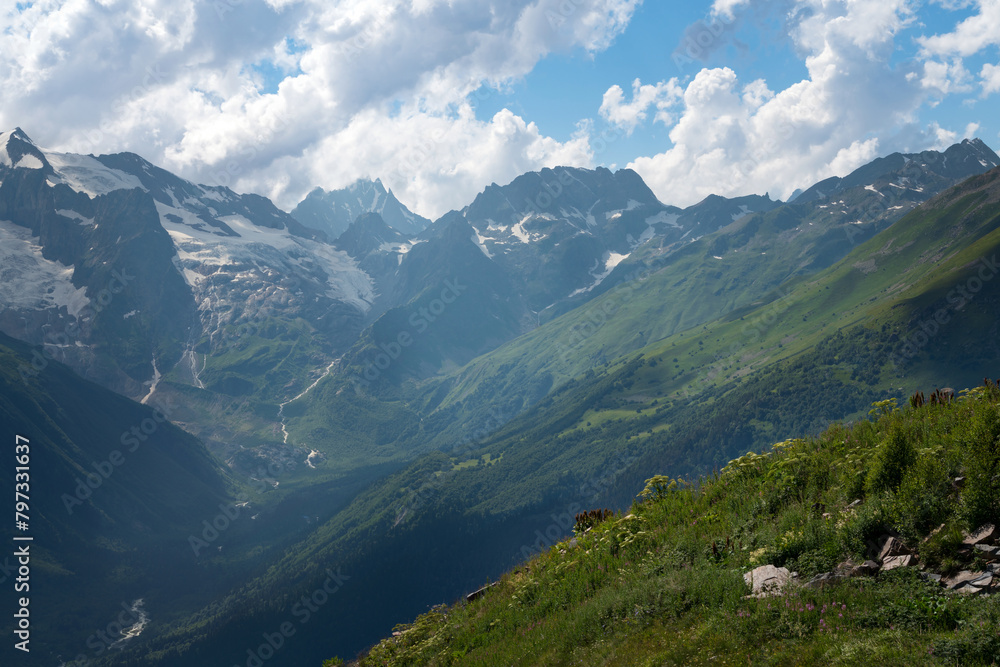 Naklejka premium View of the Alibek Gorge, the Alibek River and the mountains of the Main Caucasian Ridge, opening from the upper station of the cable car system of the Dombay ski resort, Karachay-Cherkessia, Russia