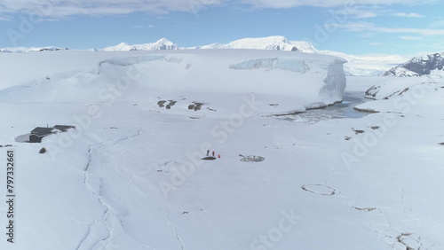 Antarctica Coast Mountain Expedition Aerial View. Arctic Extreme Cold Weather Island Coastline Snow Covered Surface. People Explore Coastline Drone Flight Zooming Out