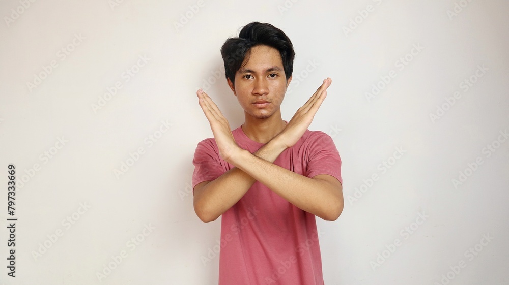 Young Asian man posing with crossed arms on an isolated white background. refusing, saying no, blocking gesture Young Asian man posing with crossed arms on an isolated white background. refusing, saying no, blocking gesture