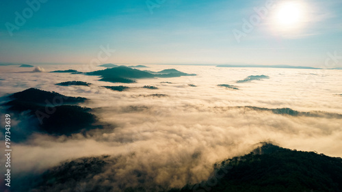 a serene landscape of mountain peaks piercing through a thick blanket of clouds under a bright sun  casting an ethereal glow  evoking tranquility and awe.