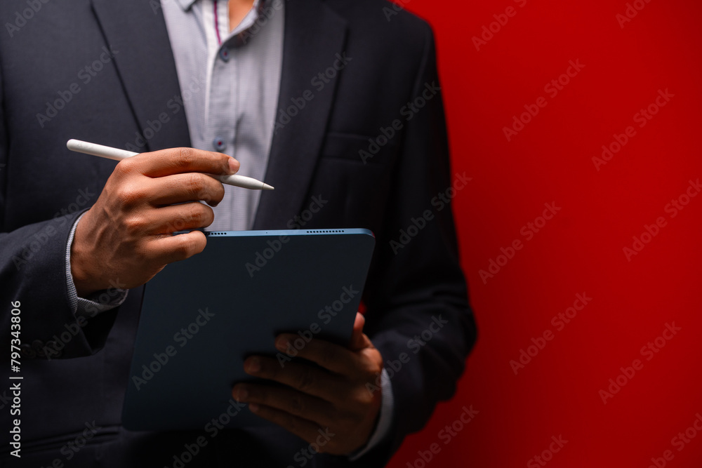Close up hands of businessman using digital tablet device isolated on red background. Close up hands of businessman using digital tablet device isolated on red background.