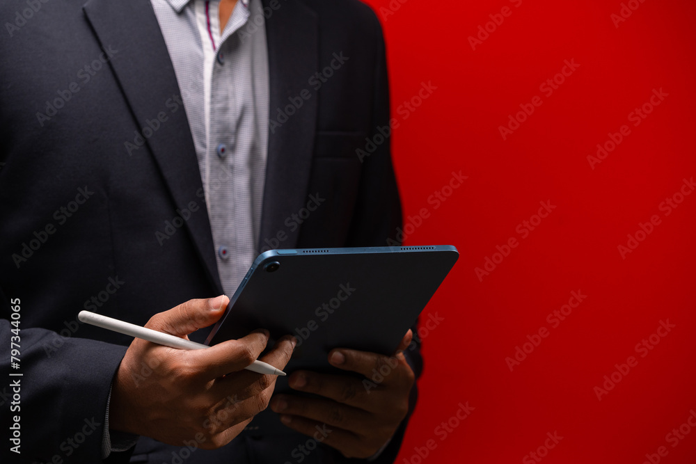 Close up hands of businessman using digital tablet device isolated on red background.