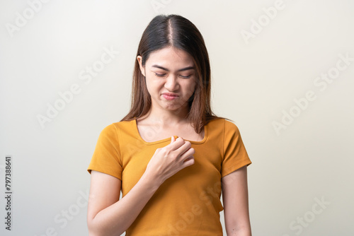 Bad smelling, deodorant asian young woman smell stink, breathing nose smelly on shirt dirty stinky laundry, disgusting from clothes after washed, smelly armpit underarm Medical health, skin body care. photo