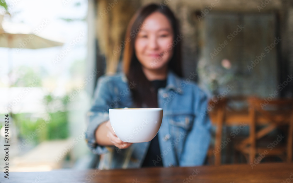 Blurred image of a woman holding and serving a cup of hot coffee in cafe Blurred image of a woman holding and serving a cup of hot coffee in cafe