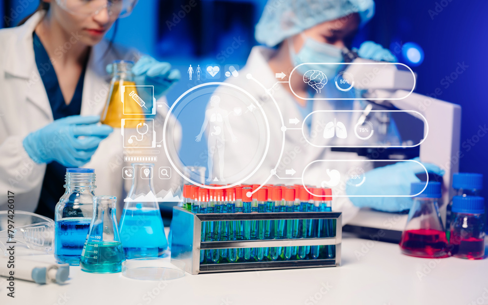 Young scientists conducting research investigations in a medical laboratory, a researcher in the foreground is using a microscope in laboratory Young scientists conducting research investigations in a medical laboratory, a researcher in the foreground is using a microscope in laboratory
