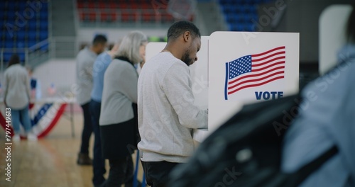 Foto Elderly male voter with bulletin in hands comes to voting booth