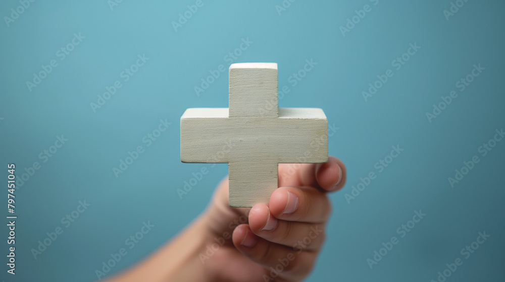Obraz premium Male hand holding plus icon on blue background. Plus sign virtual means to offer positive thing (like benefits, personal development, social network)Profit,health insurance, growth concepts.