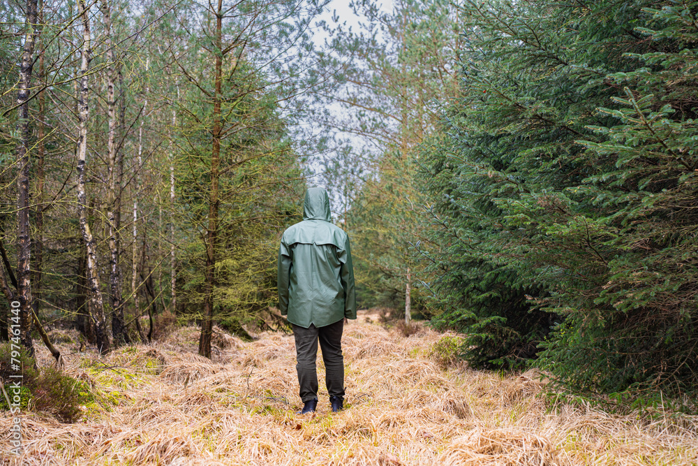 Man in green raincoat walking in the forest Man in green raincoat walking in the forest