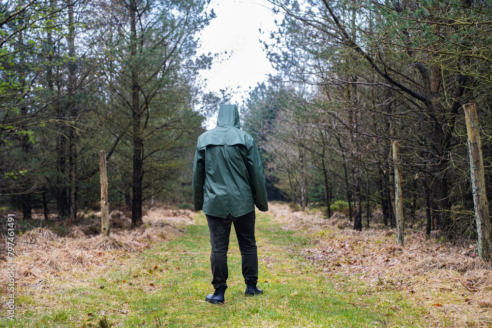 Man in green raincoat walking in the forest Man in green raincoat walking in the forest