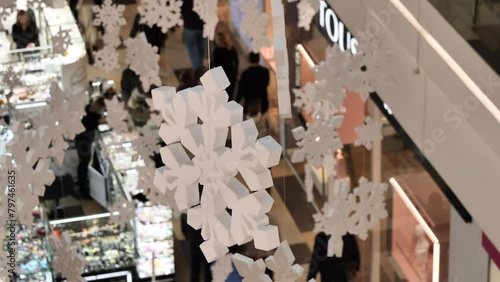 New Year atmosphere in shopping center. Holiday bustle with people looking Christmas presents. store beautifully decorated with large white snowflakes under ceiling. Concept: Christmas gift shopping