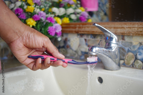 slow motion of holding toothbrush under flowing water in bathroom, closeup. © Towfiqu Barbhuiya 