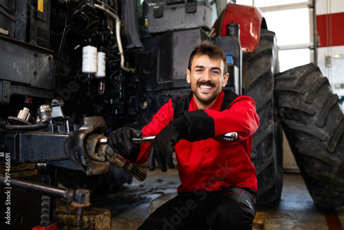 Experienced mechanic changing wheels on tractor. Service and maintenance of agricultural machinery.
