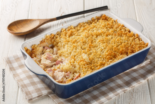 Chicken Cordon Bleu Casserole with chicken breast, chopped ham and Swiss cheese layered with creamy sauce and a buttery Panko breadcrumbs close up in the baking dish on the wooden table. Horizontal