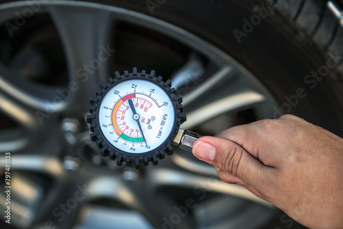 Hand car mechanic holding car tire pressure check equipment tool to checking low tire pressure inflating tires to or refill or air inflate to safety and car care service maintenance inspection. © Eakrin
