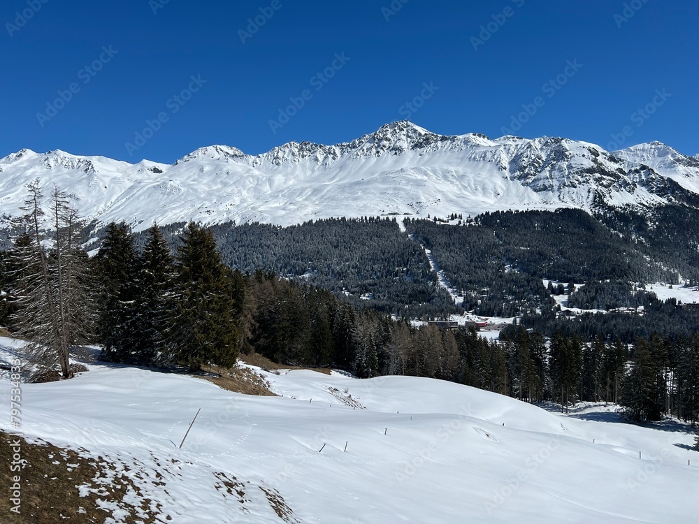 Beautiful sunlight and snow-capped alpine peaks above the Swiss tourist sports-recreational winter resorts of Valbella and Lenzerheide in the Swiss Alps - Canton of Grisons, Switzerland (Schweiz)