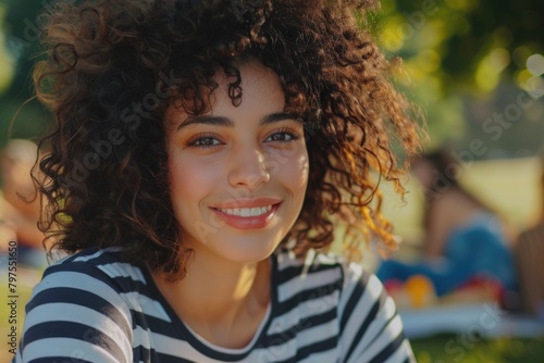 Young woman with curly hair having picnic with friends outdoors