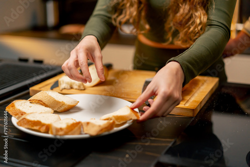 close-up of a young girl laying out sandwiches on white plate in the kitchen