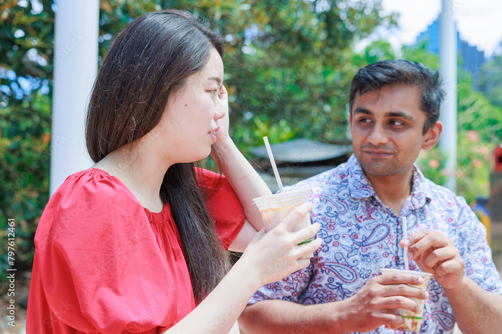 Obraz premium 屋外で冷たい飲み物を飲む国際カップル