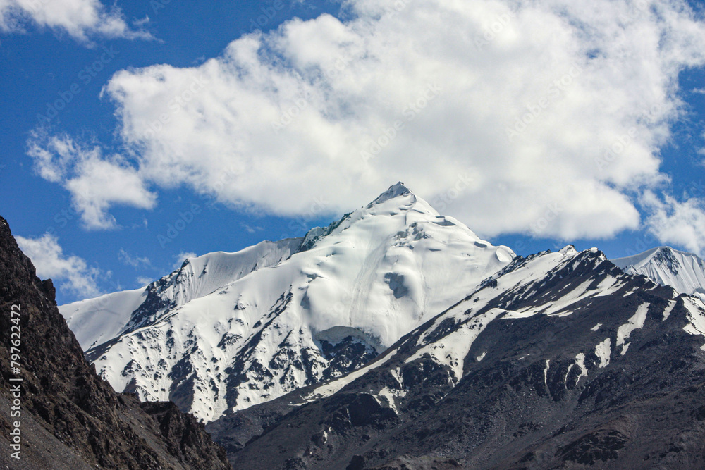 A stunning view of Snow covered mountains and clouds near Khunjerab Pass, Hunza Nagar