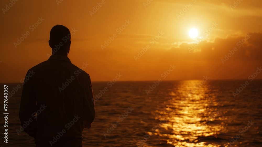 A silhouette shot of a lone seafarer standing in front of the ocean at sunset, gazing out into the vast expanse of water