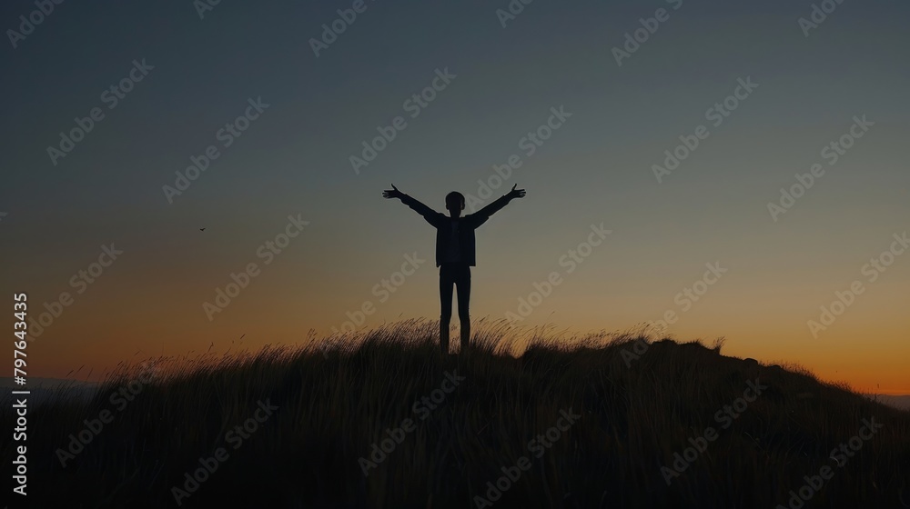 A young person standing on top of a hill during sunset