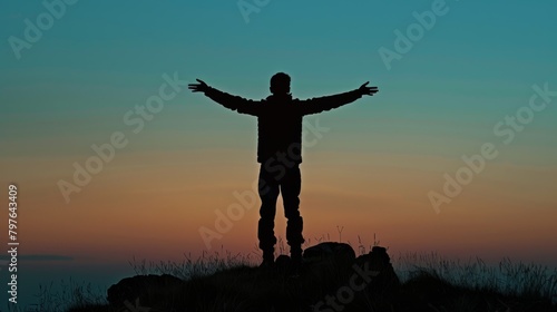 Young man standing on hilltop  arms extended outward