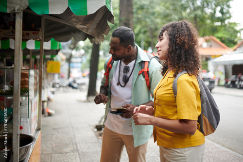 Fotografija Couple of hungry travelers standing by track of street food and choosing snacks
