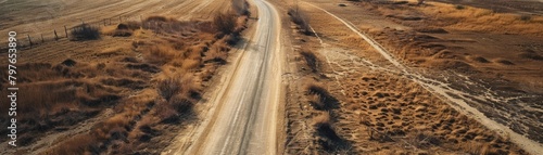 Aerial view of a desolate and forsaken empty road, the dull browns of the earth and sparse vegetation adding to the eerie atmosphere