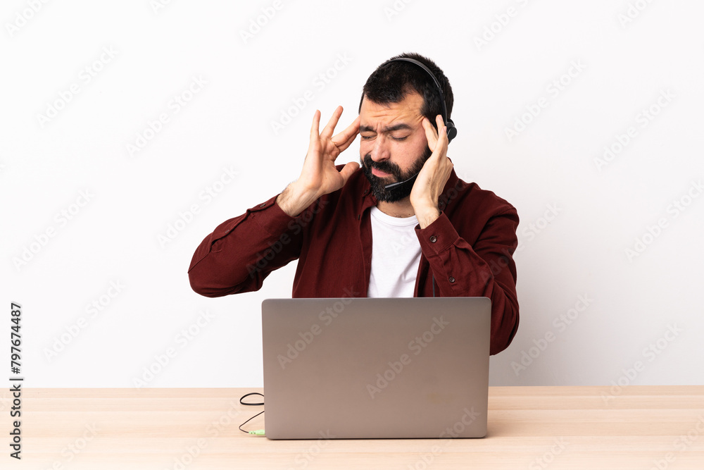 Telemarketer caucasian man working with a headset and with laptop with headache. Telemarketer caucasian man working with a headset and with laptop with headache.