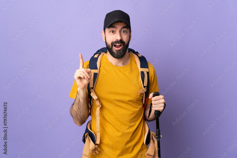 Caucasian handsome man with backpack and trekking poles over isolated background intending to realizes the solution while lifting a finger up Caucasian handsome man with backpack and trekking poles over isolated background intending to realizes the solution while lifting a finger up