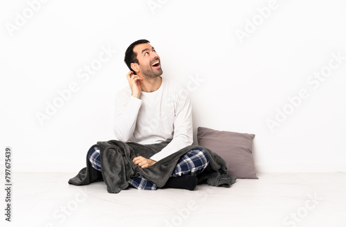 Caucasian man in pajamas sitting on the floor at indoors thinking an idea © luismolinero