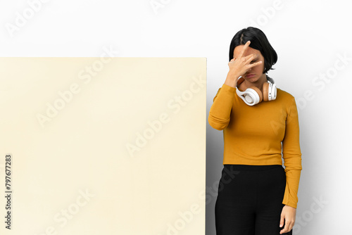 Young woman listening music with a big empty placard over isolated background with headache photo