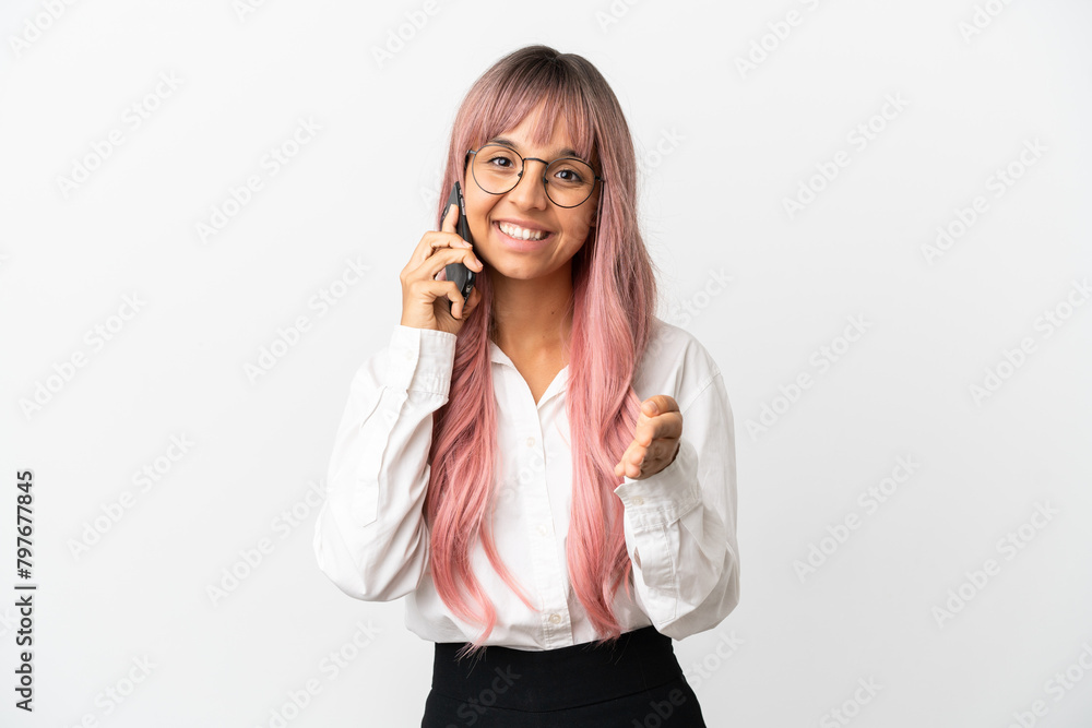 Young business mixed race woman with pink hair holding a mobile isolated on pink background shaking hands for closing a good deal Young business mixed race woman with pink hair holding a mobile isolated on pink background shaking hands for closing a good deal