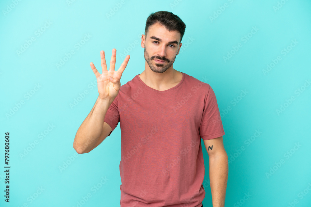 Fototapeta premium Young caucasian man isolated on blue background happy and counting four with fingers