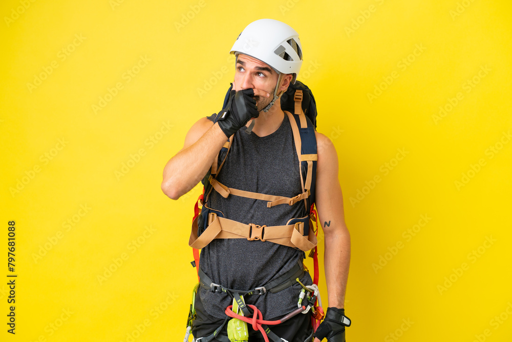 Young caucasian rock climber man isolated on yellow background having doubts and with confuse face expression Young caucasian rock climber man isolated on yellow background having doubts and with confuse face expression