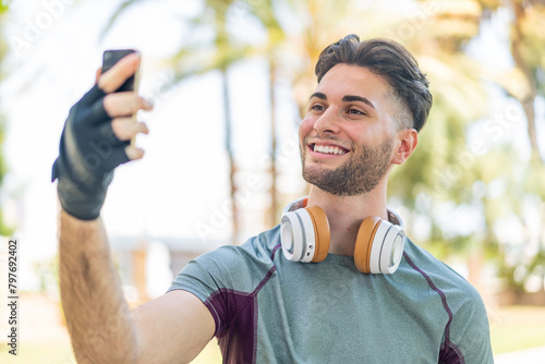 Young handsome man wearing sport wear and taking a selfie with the mobile